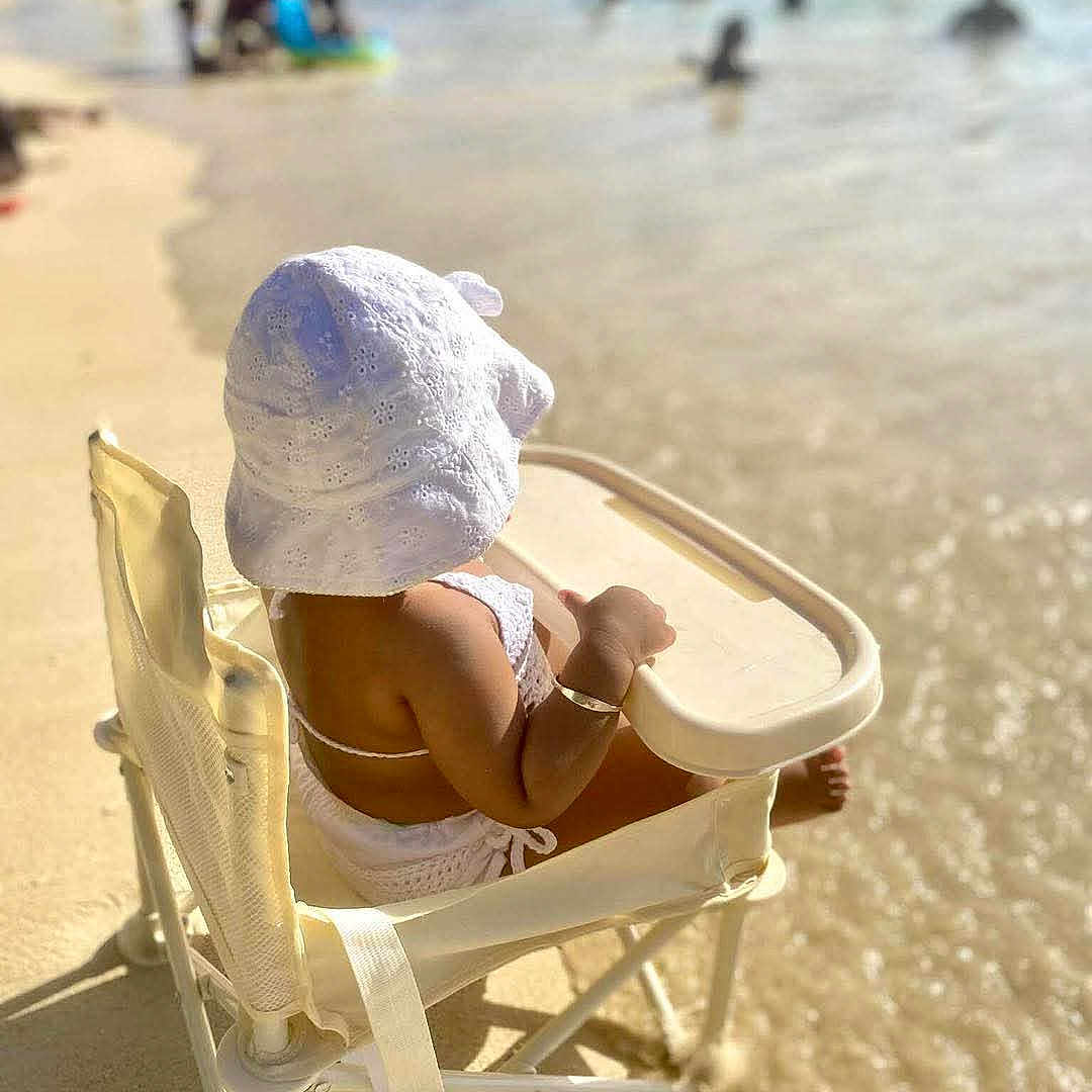 Aurora is registered to the contest to win money with this photo: baby, beach, chair, child, hat, holiday, ocean, outdoor, relaxation, sand, sea, sitting, small_person, summer, sunhat, sunlight, swimwear, vacation, water, waves