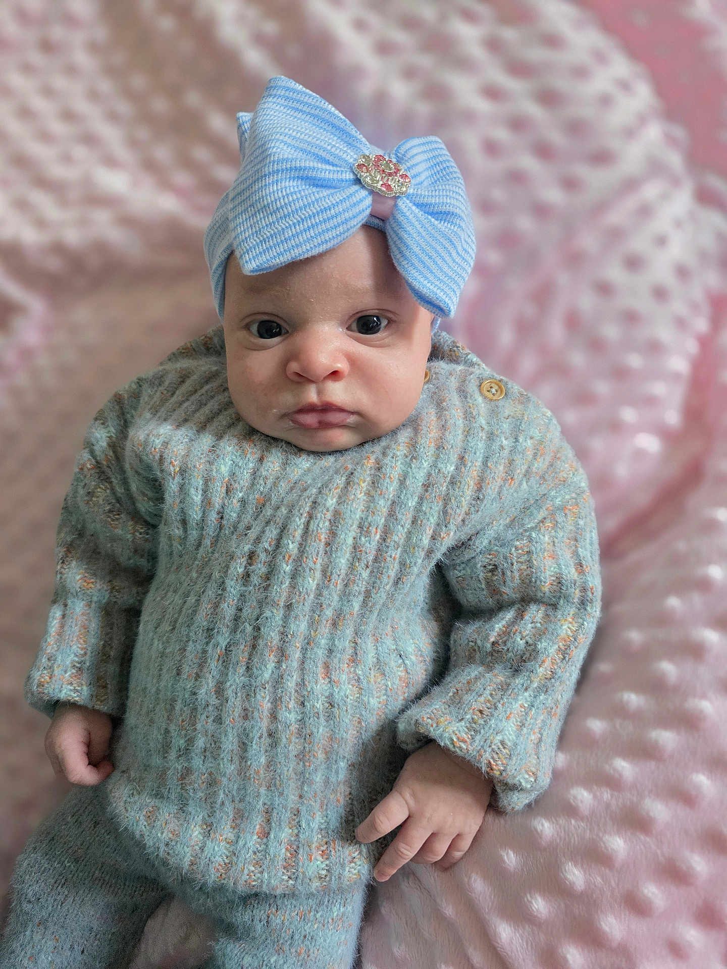 Aurora joined the competition — help win amazing prizes! baby, infant, blue_bow, headband, knit_sweater, knit_pants, pink_blanket, soft_texture, closeup, person, cute, child, portrait, indoor, cozy, warm_clothing, small_hands, expression, looking_at_camera, sitting