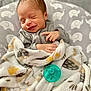 baby, bed, blanket, clothing, cozy, cute, face, gray, hand, infant, nap, newborn, pacifier, pattern, peaceful, sleeping, smiling, soft, wrapped, yellow