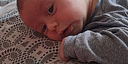 Milhan participe au concours pour gagner de l'argent avec cette photo : baby, infant, blanket, pattern, bed, furniture, dresser, clothing, face, head, skin, sleepwear, indoors, resting, person, child, young, portrait, soft_light, curious