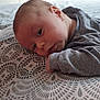 baby, infant, blanket, pattern, bed, furniture, dresser, clothing, face, head, skin, sleepwear, indoors, resting, person, child, young, portrait, soft_light, curious