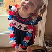 Lainey joined the competition — help win amazing prizes! child, girl, red_hair, pigtails, dress, flower_lei, navy_blue, anchors, smile, indoors, door, rug, sandals, playful, happy, person, standing, natural_light, curly_hair, floor