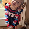 child, girl, red_hair, pigtails, dress, flower_lei, navy_blue, anchors, smile, indoors, door, rug, sandals, playful, happy, person, standing, natural_light, curly_hair, floor
