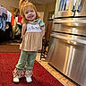 Lainey is registered to the contest to win money with this photo: child, girl, red_hair, smiling, standing, indoor, kitchen, refrigerator, carpet, clothing, white_shoes, ruffled_pants, ceiling_fan, door, furniture, home, light, portrait, happy, person