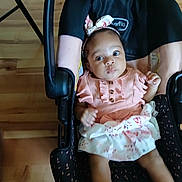 Lilah Perry joined the competition — help win amazing prizes! baby, infant, car_seat, pink_dress, headband, floral_pattern, wooden_floor, baby_clothing, child, person, indoor, hand, footwear, seat, cute, portrait, young_child, baby_girl, looking, sitting