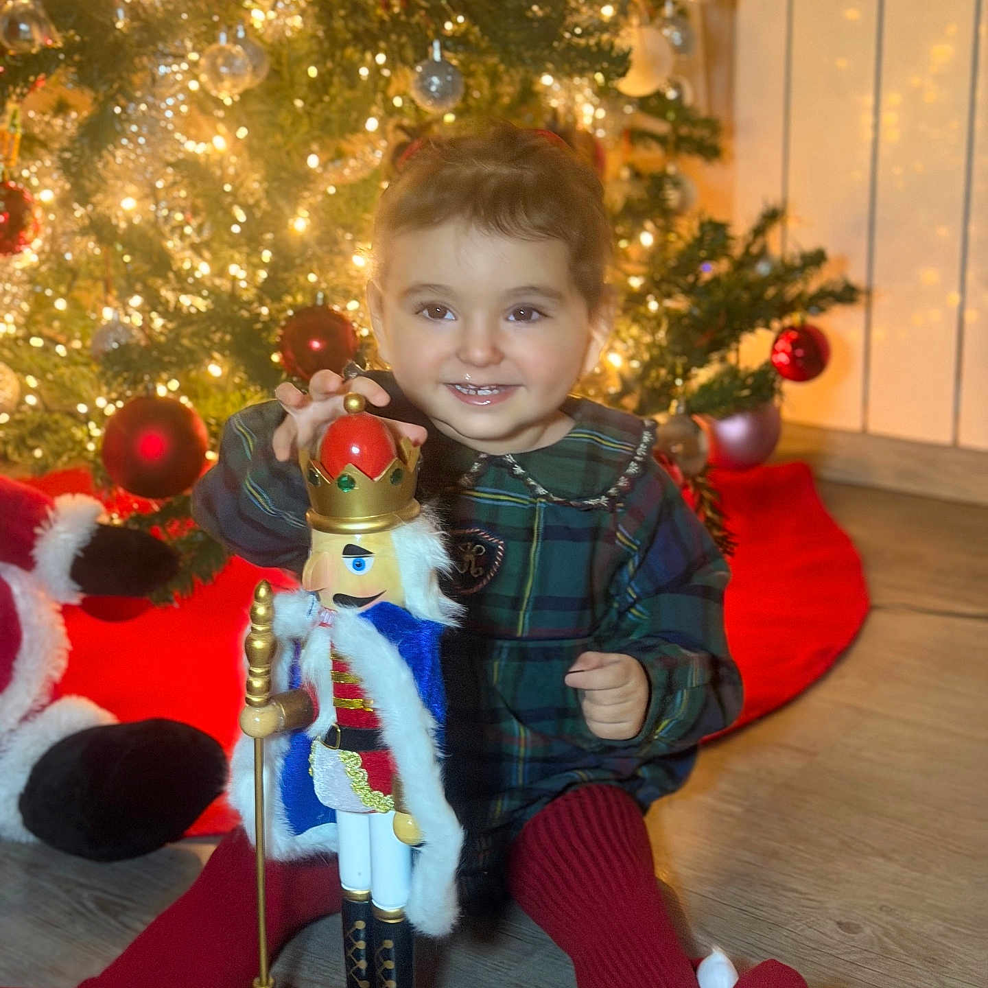 Lydia Doğa a rejoint le concours — aidez-le/la à gagner de superbes lots ! child, christmas_tree, cute, decorations, festive, floor, green_dress, happy, holiday, holiday_decor, indoors, lights, nutcracker, ornaments, red_tights, seasonal, smiling, toddler, toy, wood_floor
