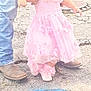 child, toddler, pink_dress, floral_headband, boots, jeans, adult_hand, pavement, manhole_cover, outdoor, walking, support, curious, footwear, flower_accessory, casual_clothing, baby_shoes, street, helping_hand, sidewalk