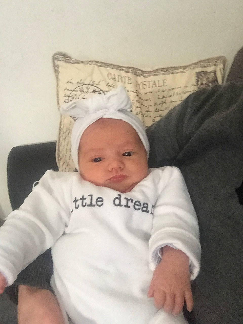 Enola participe au concours pour gagner de l'argent avec cette photo : baby, baby_products, baby_sleeping, baby_toddler_clothing, bedding, cap, cheek, child, comfort, couch, hat, headgear, linens, person, room, sitting, sleeve, smile, t_shirt, throw_pillow