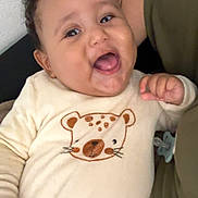 Izaak participe au concours pour gagner de l'argent avec cette photo : baby, child, smiling, cute, onesie, bear_design, curly_hair, indoor, person, happy, infant, cozy, clothing, face, hand, pacifier, blanket, adult_arm, skin, portrait