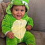 baby, child, dinosaur_costume, green_costume, smiling, couch, plush, cute, happy, infant, socks, indoors, soft_fabric, hood, teeth, seated, portrait, person, cozy, warm