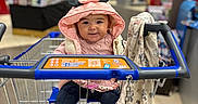 Esmée participe au concours pour gagner de l'argent avec cette photo : baby, shopping_cart, store, indoor, child, smiling, clothing, hood, sweater, socks, fabric, retail, aisle, shopping, person, cute, toy, seat, happy, supermarket