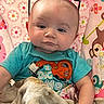 baby, child, glasses, blue_shirt, blanket, patterned_background, floral_pattern, animal_pattern, cute, indoors, portrait, sitting, soft_texture, toddler, young_child, clothing, face, head, expression, colorful