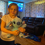 Brooklynn joined the competition — help win amazing prizes! casual_clothing, child, curtains, dark_pants, family_room, home, hugging, indoor, living_room, playful, plush_toy, portrait, recliner, sitting, smiling, sofa, stitch, t_shirt, television, wooden_floor
