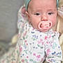 baby, infant, pacifier, headband, floral_onesie, blanket, closeup, cute, child, soft_focus, indoors, sleepwear, portrait, young_child, resting, comfort, skin, hand, expression, lying_down