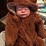 Levi is registered to the contest to win money with this photo: baby, child, costume, bear, brown, sleepy, cute, fuzzy, hood, clothing, infant, person, indoor, soft, warm, face, hand, seated, carpet, book