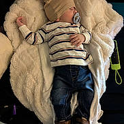 Levi is registered to the contest to win money with this photo: baby, blanket, child, comfort, couch, cozy, cute, furniture, hat, indoor, infant, jeans, pacifier, person, relaxation, resting, shoes, sleeping, soft_texture, striped_clothing