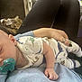Levi is registered to the contest to win money with this photo: baby, sleeping, pacifier, pajamas, dinosaur, infant, person, hand, clothing, lap, cozy, indoor, cute, rest, child, footwear, soft, relaxation, home, comfort