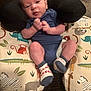 baby, infant, blue_onesie, socks, animal_print, cushion, neck_pillow, indoor, cute, child, person, resting, comfort, soft_furniture, face, head, legs, hands, expression, newborn