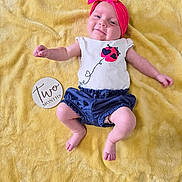 Ryder is registered to the contest to win money with this photo: baby, infant, smiling, pink_headband, bow, yellow_blanket, milestone_disc, two_months, onesie, shorts, bare_feet, legs, arms, face, portrait, indoor, soft_texture, cozy, cute, laying_down