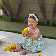 Sophia is registered to the contest to win money with this photo: baby, child, lemon, fruit, dress, headband, blanket, outdoor, grass, smile, happy, sitting, cute, playful, summer, garden, nature, person, infant, portrait