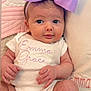 baby, infant, bow, headband, onesie, clothing, face, hands, legs, pillow, quilt, text_embroidery, cute, portrait, child, soft_texture, pink, purple, newborn, smiling