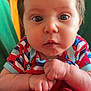 baby, child, close_up, face, hands, indoor, curious, expression, red_blanket, striped_clothing, cute, portrait, infant, young_child, skin, person, human, resting, colorful, casual