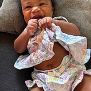 Divinity joined the competition — help win amazing prizes! baby, infant, smiling, happy, curly_hair, couch, clothing, floral_pattern, hand, face, skin, torso, cute, playful, indoors, child, portrait, fabric, button, relaxing