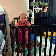 Zaeden joined the competition — help win amazing prizes! baby, crib, child, smiling, toy, mobile, stuffed_animal, bedroom, blanket, furniture, infant, happy, person, standing, playtime, interior, mattress, curtain, nightstand, lamp