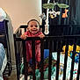 baby, crib, child, smiling, toy, mobile, stuffed_animal, bedroom, blanket, furniture, infant, happy, person, standing, playtime, interior, mattress, curtain, nightstand, lamp
