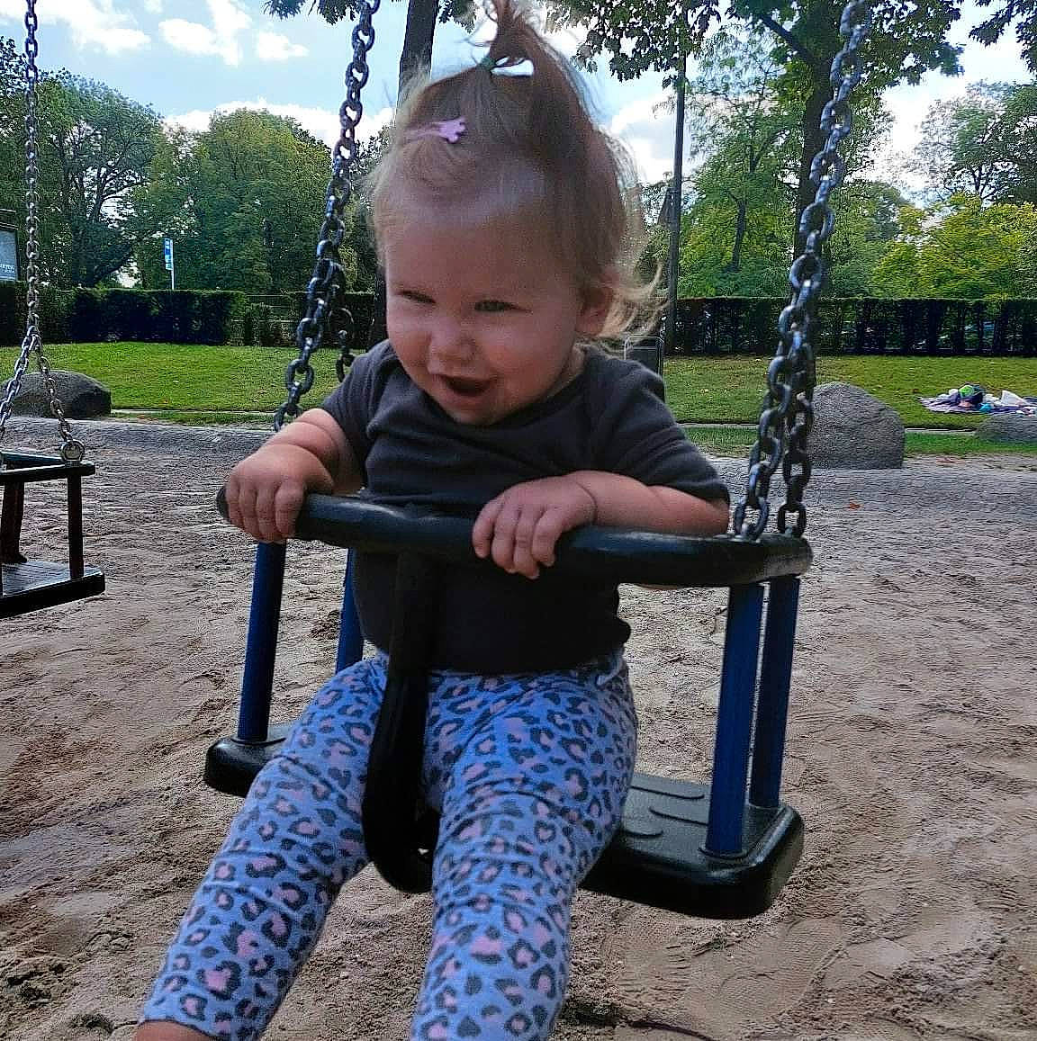 Emilia participe au concours pour gagner de l'argent avec cette photo : baby, baby_toddler_clothing, child, city, cloud, electric_blue, fun, grass, happy, leisure, outdoor_furniture, outdoor_play_equipment, person, plant, playground, sitting, sleeve, smile, swing, toddler