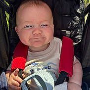 Parker joined the competition — help win amazing prizes! baby, blanket, child, clothing, cute, face, hand, happy, infant, outdoor, person, portrait, red_harness, relaxation, seat_belt, shadow, smile, stroller, sunlight, teething_toy
