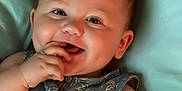Parker is registered to the contest to win money with this photo: baby, blue, cheeks, child, clothing, cushion, cute, face, fingers, hand, happy, indoors, infant, palm_tree_pattern, person, portrait, resting, sleeveless, smiling, soft