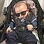 baby, sunglasses, stroller, sleeping, child, clothing, seatbelt, mickey_mouse, footwear, casual_wear, indoor, infant, person, portrait, relaxing, cute, baby_clothes, headwear, comfort, resting