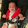 Nino participe au concours pour gagner de l'argent avec cette photo : baby, smiling, stroller, red_straps, onesie, infant, happy, child, seatbelt, indoor, person, cute, playful, baby_toy, pacifier, black_stroller, clothing, young_child, sitting, cheerful