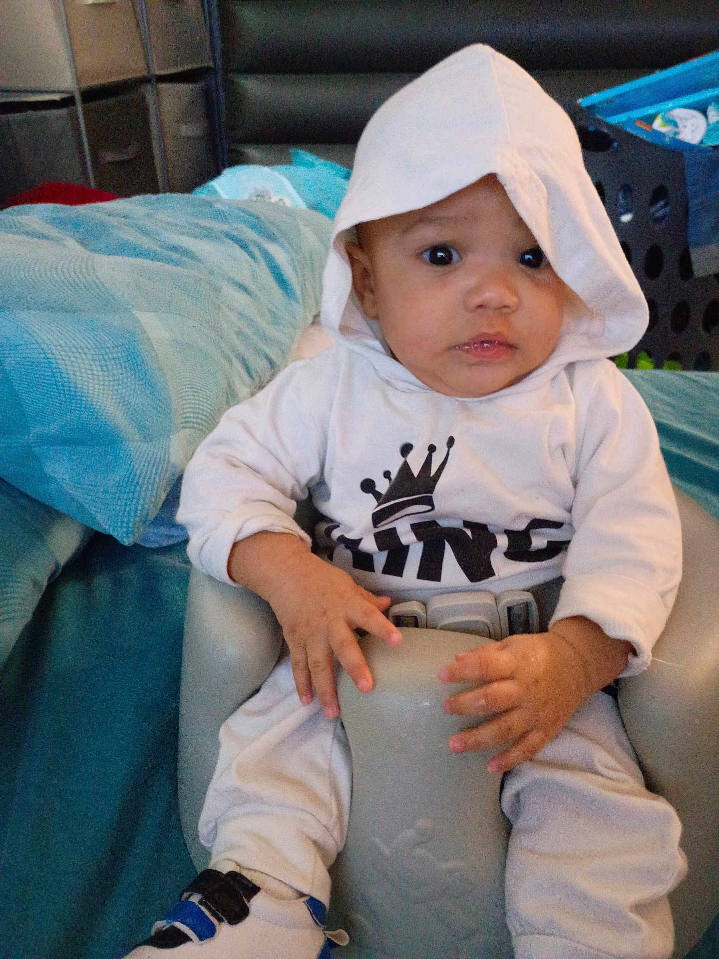 Octavious joined the competition — help win amazing prizes! baby, hoodie, white_clothing, baby_seat, indoor, curious_expression, wide_eyes, hand_grip, blue_shoes, bedspread, laundry_basket, seated, child, infant, casual_clothing, portrait, person, young_child, crown_graphic, comfortable