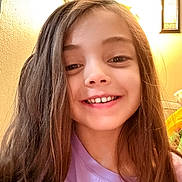 Alyssa is registered to the contest to win money with this photo: child, smile, girl, long_hair, purple_shirt, indoor, wall, framed_picture, portrait, face, happy, person, young, casual_clothing, lighting, home, closeup, hair, expression, background
