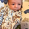 baby, infant, onesie, animal_print, blanket, dinosaur, cute, face, portrait, clothing, child, lying_down, pattern, sleepwear, young_child, indoors, soft, adorable, baby_girl, baby_boy