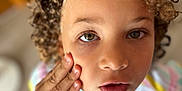 Jasmine Keira participe au concours pour gagner de l'argent avec cette photo : child, curly_hair, face, hand, portrait, close_up, eyes, expression, skin, person, casual_clothing, indoor, blurred_background, colorful_shirt, young, natural_light, looking, curiosity, human, head