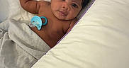 Ahmaad is registered to the contest to win money with this photo: awake, baby, bed, bedding, bedroom, blanket, brown_skin, candid, child, cozy, curly_hair, dark_hair, indoor, infant, lying_down, pacifier, photography, pillow, portrait, wide_eyes