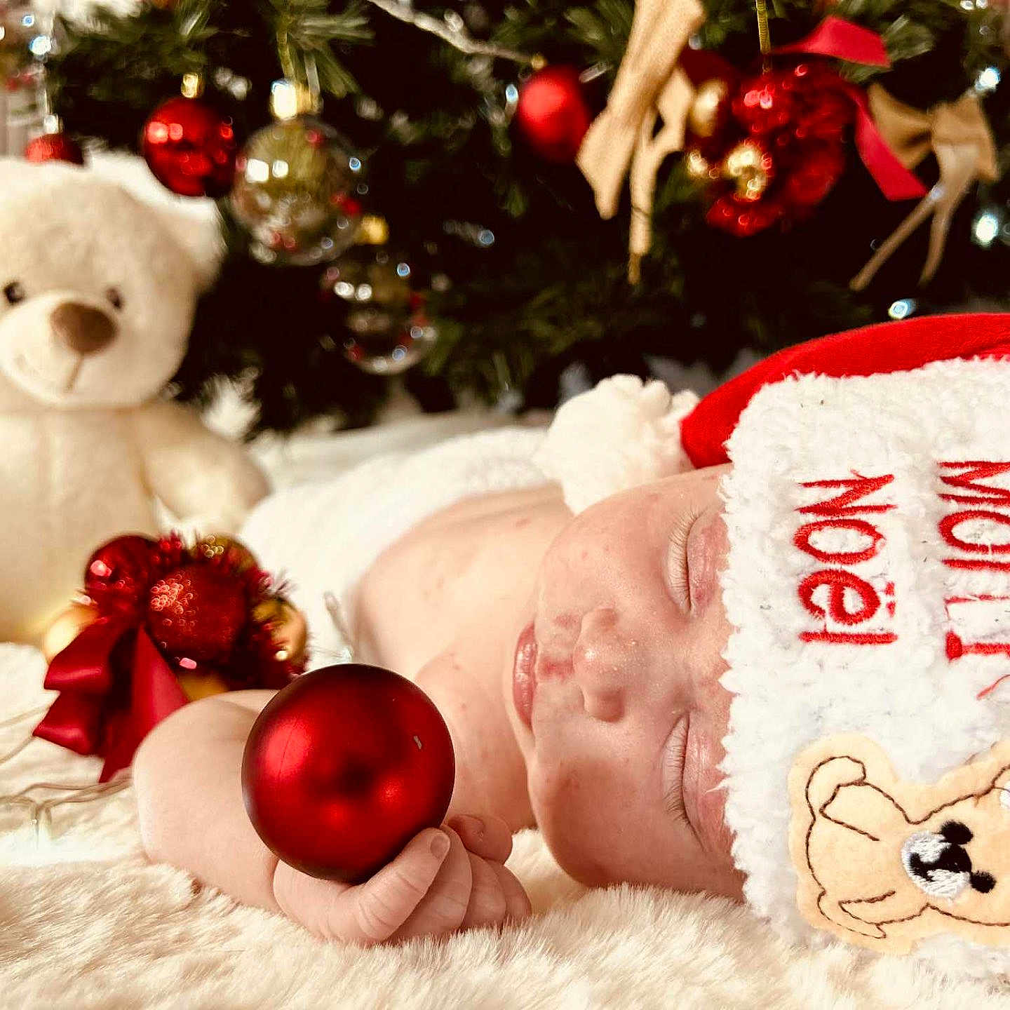 Hannah a rejoint le concours — aidez-le/la à gagner de superbes lots ! baby, christmas_ornament, christmas_tree, close_up, cozy, cute, decorations, face, festive, hand, holiday, holiday_season, infant, plush_toy, red, santa_hat, sleeping, soft_texture, teddy_bear, white