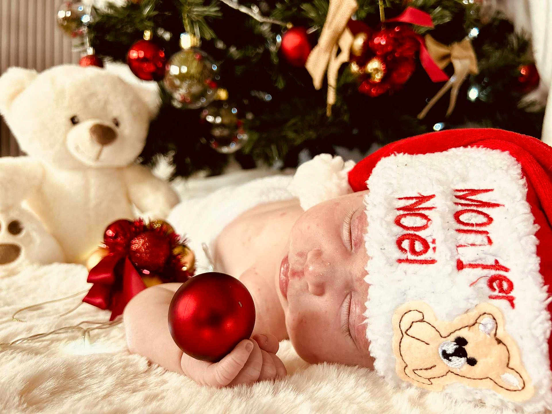 Hannah a rejoint le concours — aidez-le/la à gagner de superbes lots ! baby, sleeping, santa_hat, christmas_ornament, holiday, plush_toy, teddy_bear, christmas_tree, decorations, red, white, soft_texture, close_up, festive, cute, infant, hand, face, holiday_season, cozy
