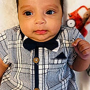 Kaleth is registered to the contest to win money with this photo: baby, blanket, bow_tie, button, checkered, child, clothing, cute, expression, eyes, face, hand, head, indoors, infant, lying_down, pattern, portrait, skin, young