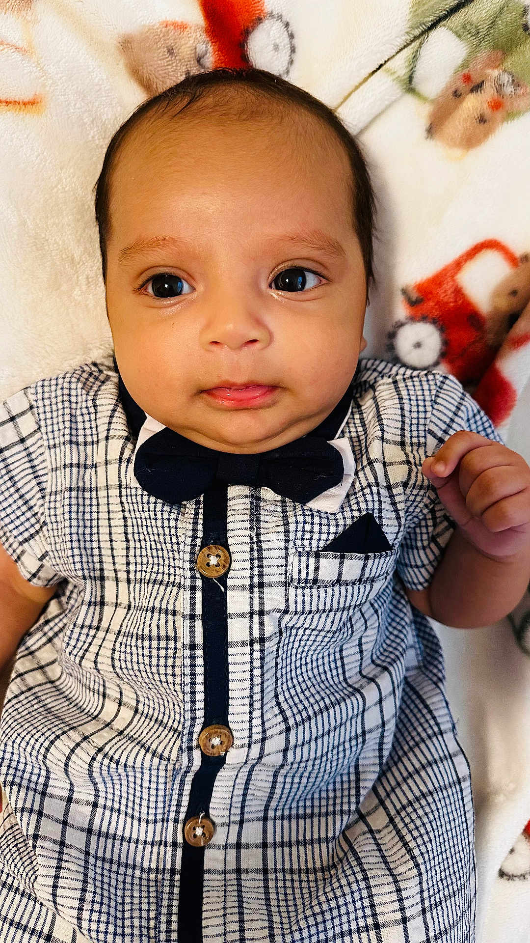 Kaleth is registered to the contest to win money with this photo: baby, blanket, bow_tie, button, checkered, child, clothing, cute, expression, eyes, face, hand, head, indoors, infant, lying_down, pattern, portrait, skin, young