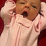baby, infant, pink_onesie, yawning, stretching, diapers, red_background, sleepy, cute, newborn, child, portrait, clothing, fabric_texture, small_hands, head, face, expression, cozy, resting
