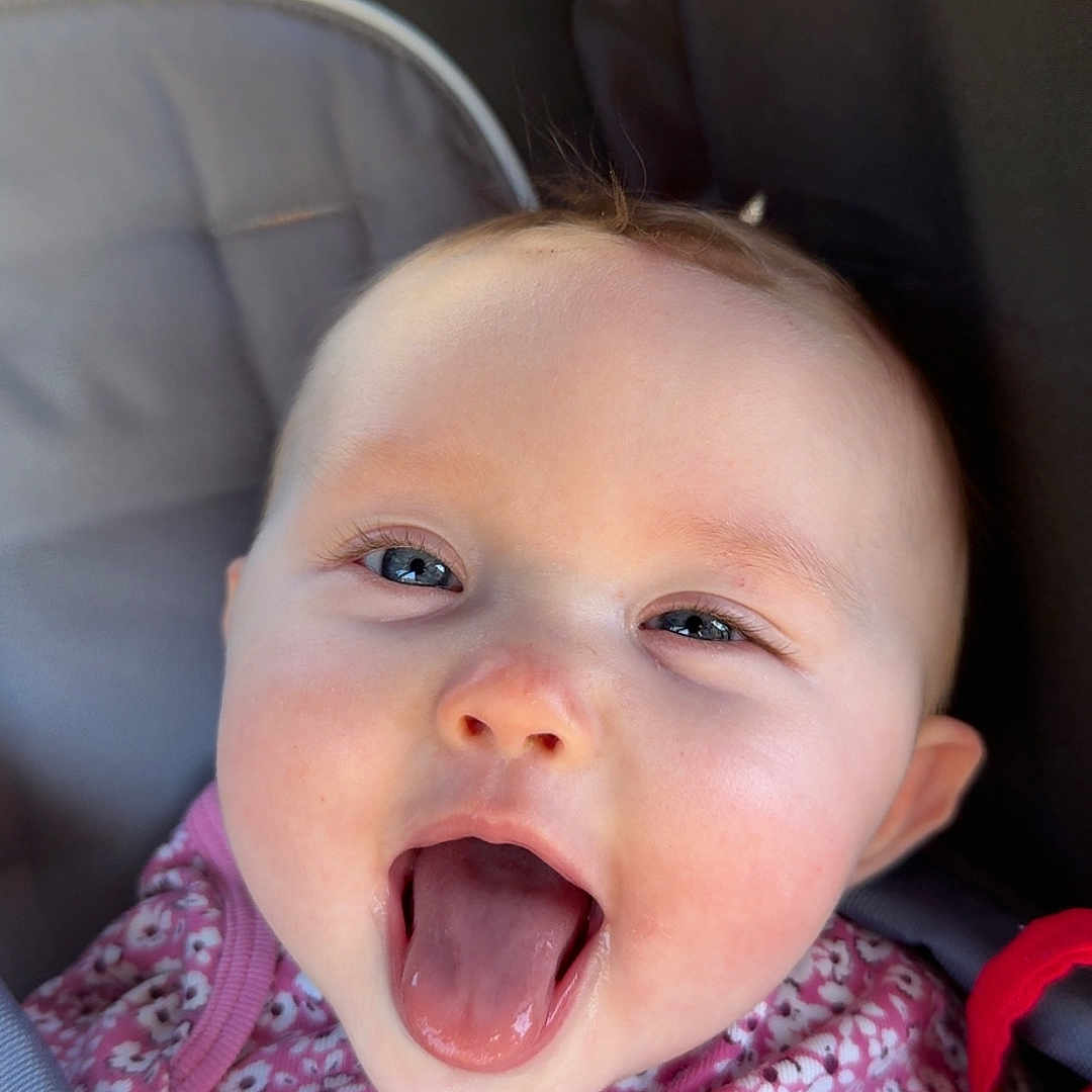 Scarlett joined the competition — help win amazing prizes! baby, bodypart, car, car_interior, carseat, cushion, face, happy, head, homedecor, laughing, mouth, newborn, person, photography, portrait, stroller, tongue, transportation, vehicle