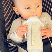Hermanzo participe au concours pour gagner de l'argent avec cette photo : baby, baby_carrier, child, closeup, clothing, cute, face, feeding, hands, head, holding, indoors, infant, milk, milk_bottle, milk_feeding, portrait, sitting, striped, young