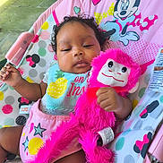 Cassidy is registered to the contest to win money with this photo: baby, infant, toy, plush_toy, pink, mickey_mouse, minnie_mouse, baby_seat, colorful, outdoor, child, cute, relaxed, clothing, bib, patterned, smile, hand, face, curly_hair