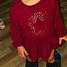 child, toddler, boots, maroon_dress, star_pattern, blue_eyes, curly_hair, indoor, wooden_floor, standing, looking_up, casual_clothing, flooring, small_child, footwear, person, portrait, cute, curious, fashion