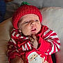 Huxley joined the competition — help win amazing prizes! baby, infant, red_hat, striped_clothing, santa_claus_print, red_clothing, white_stripes, knit_hat, pom_pom, cute, child, newborn, lying_down, soft_surface, holiday_outfit, christmas_theme, indoors, portrait, clothing, face
