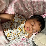 Seraphina is registered to the contest to win money with this photo: baby, sleeping, blanket, bed, floral_outfit, infant, soft_texture, cushion, peaceful, resting, child, indoors, cute, portrait, cozy, person, comfort, toddler, sleep, head